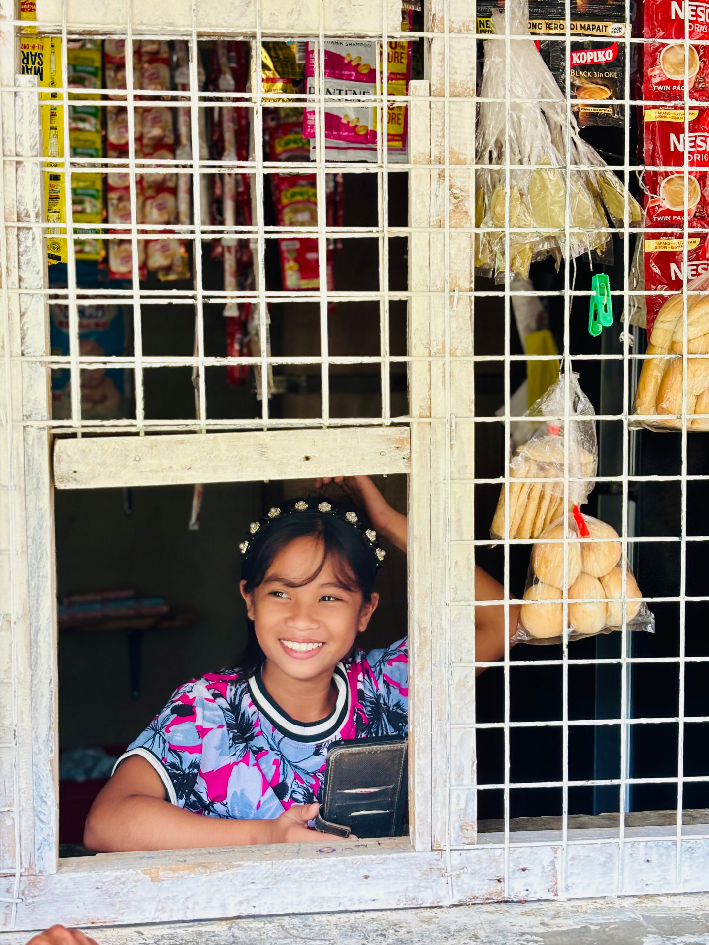 A girl in a beaded headband at a village shop window