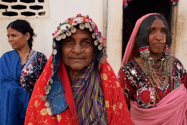 Three women in red, pink and blue veils with silver jewellery