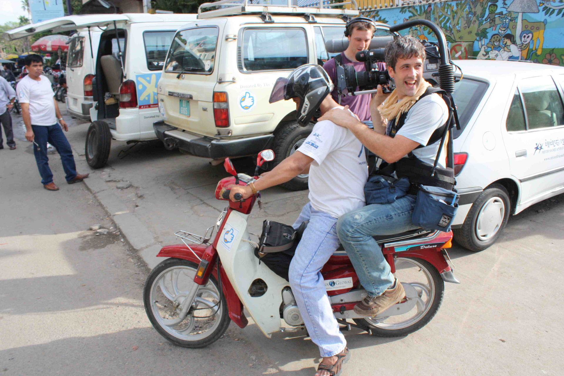 Éli filming from the back of a moped in Cambodia, camera on his shoulder