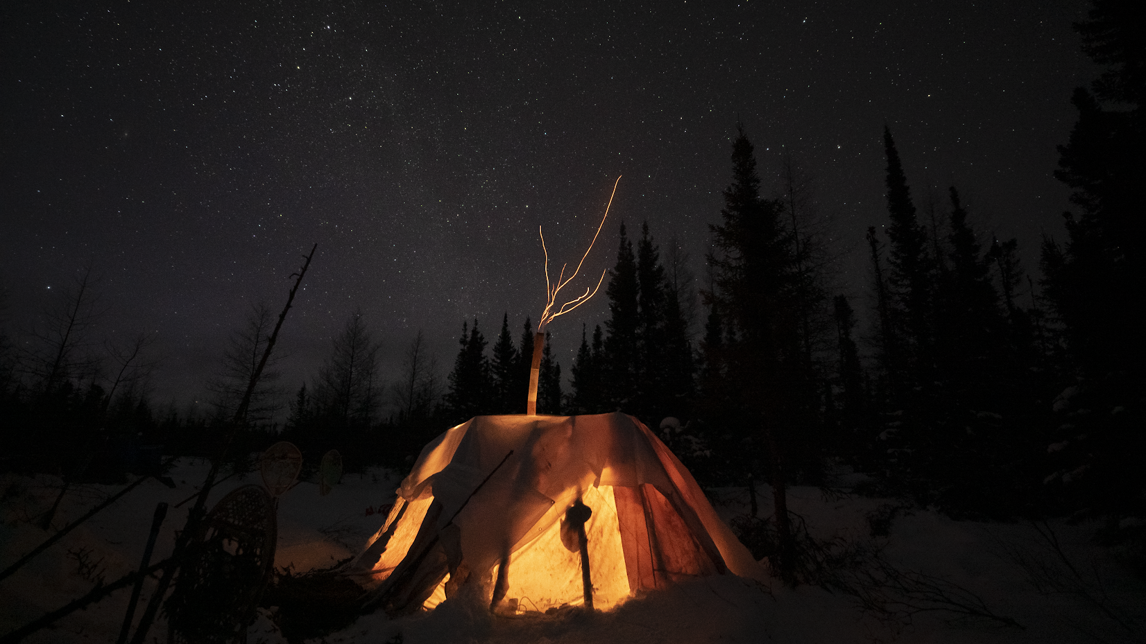 Glowing canvas tent under a starry winter sky