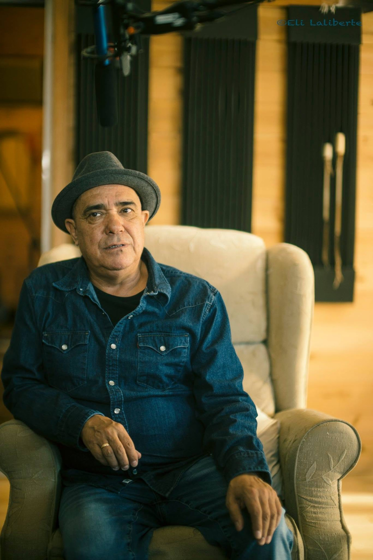 Florent Vollant in a grey hat, seated in an armchair during an interview
